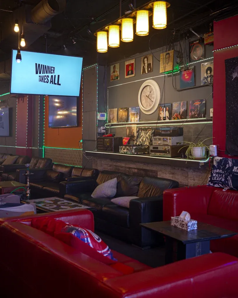 Red and black seating under the vinyl record wall, with sports on the screens